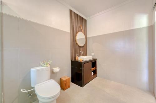 a bathroom with a toilet and a sink and a mirror at Kelingking Tropical in batumadeg