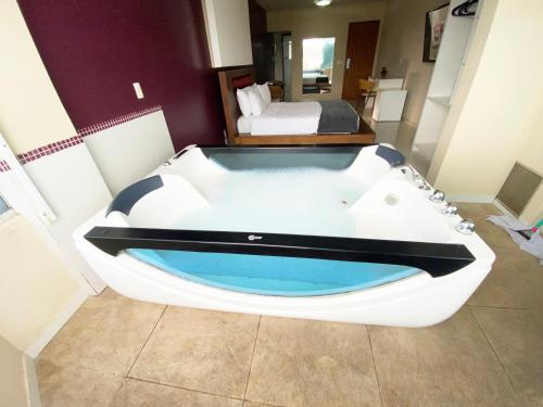 a bath tub in a room with a bed at Emirates Hotel & Suites in Santana do Livramento