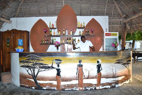 a bar with a man standing behind a counter with people at Union Beach Bungalow in Nungwi