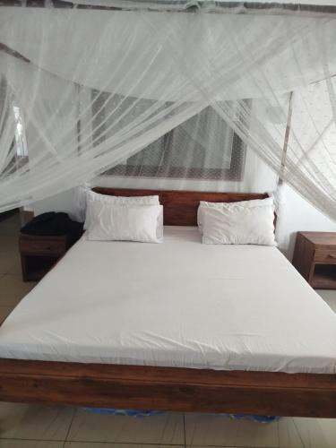 ein Bett mit weißen Laken und Kissen in einem Zimmer in der Unterkunft Villa meuble a louer Anakao in Anakao