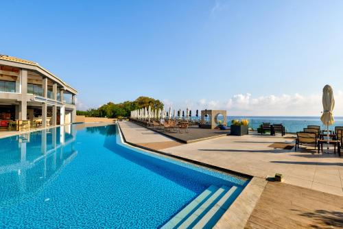 a swimming pool with a view of the ocean at Cavo Orient Beach Hotel & Suites in Tragaki