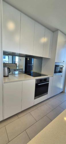 a kitchen with white cabinets and black appliances at Luxury Barton Apartment with Views in Prime Location in Barton