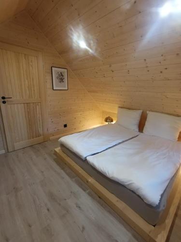 a bedroom with a bed in a wooden cabin at Domek Pod Jemiołami - Mały Głęboczek in Mały Głęboczek