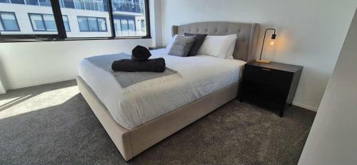 a bedroom with a bed with a black cat sitting on it at Luxury Barton Apartment with Views in Prime Location in Barton