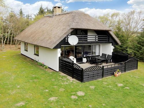 a house with a thatched roof with a deck at Holiday Home Rigitte - 1-5km from the sea by Interhome in Pandrup