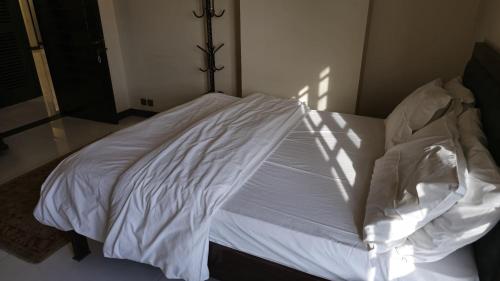a white bed in a bedroom with the light shining on it at Home Sweet Home in Karachi