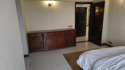 a bedroom with a bed and a wooden cabinet at Home Sweet Home in Karachi