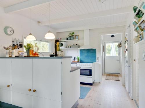 a kitchen with white cabinets and blue accents at Holiday Home Thersten - 500m to the fjord by Interhome in Løgsted