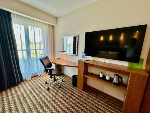 a hotel room with a desk and a flat screen tv at Hampton by Hilton Gdansk Airport in Gdańsk-Rębiechowo