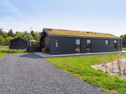 una casa negra con entrada de grava en Holiday Home Dyke - 1-5km from the sea by Interhome, en Saltum