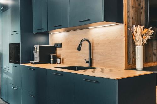 a kitchen with blue cabinets and a sink at CHALET TEKA LES GETS - Appartement Adret in Les Gets