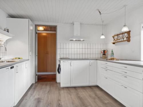 a white kitchen with white cabinets and a wooden floor at Holiday Home Justine - 600m from the sea by Interhome in Fjerritslev