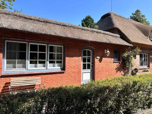 a red brick house with a thatched roof at 3 Zimmer Wohnung in Reetdachanwesen Hus op de Duen in Sankt Peter-Ording