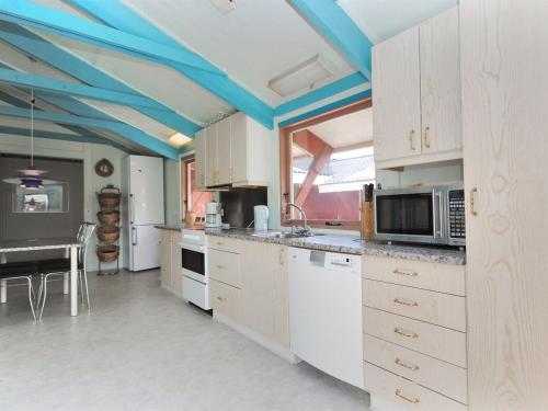 a kitchen with white cabinets and a blue ceiling at Holiday Home Momme - 500m from the sea by Interhome in Fjerritslev