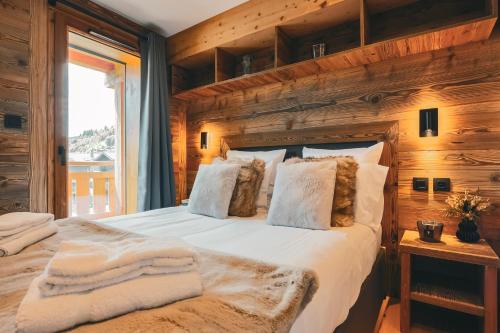 a bedroom with a large bed with a wooden wall at CHALET TEKA LES GETS - Appartement Adret in Les Gets