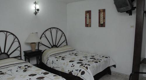 two beds sitting next to each other in a bedroom at Hotel Posada del Angel in Mérida