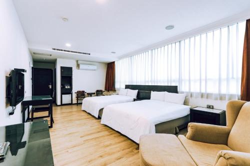 a hotel room with two beds and a couch at Herkang Hotel in Taichung