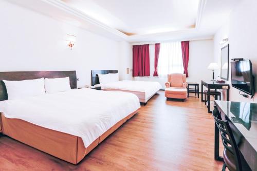 a hotel room with two beds and a television at Herkang Hotel in Taichung