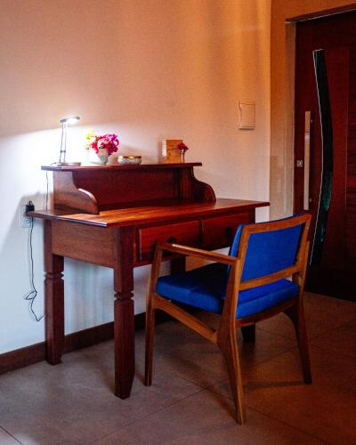 a wooden desk with a blue chair and a piano at Hotel de Charme Illuminare Stile in Fortim