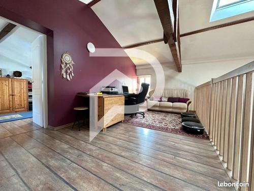 a living room with purple walls and a desk at Logement indépendant au calme in Caudrot
