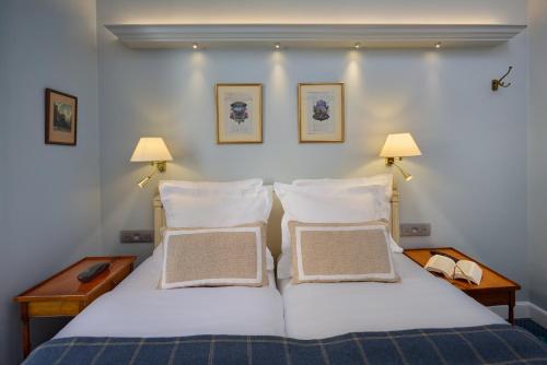 a bedroom with a bed with two pillows and two lamps at Relais Du Louvre in Paris