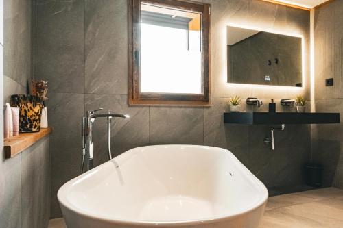 a white bath tub in a bathroom with a mirror at CHALET TEKA LES GETS - Appartement Adret in Les Gets