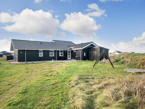 una casa nera su una collina con un campo erboso di Holiday Home Rodna - 452m from the sea by Interhome a Hirtshals