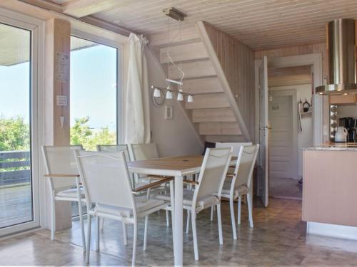 a dining room with a wooden table and white chairs at Holiday Home Brun - 60m from the sea by Interhome in Læsø