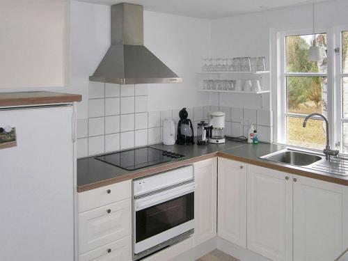 a white kitchen with a sink and a stove top oven at Holiday Home Siggi - 400m from the sea by Interhome in Jerup