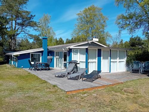 a blue and white house with chairs and a grill at Holiday Home Siggi - 400m from the sea by Interhome in Jerup