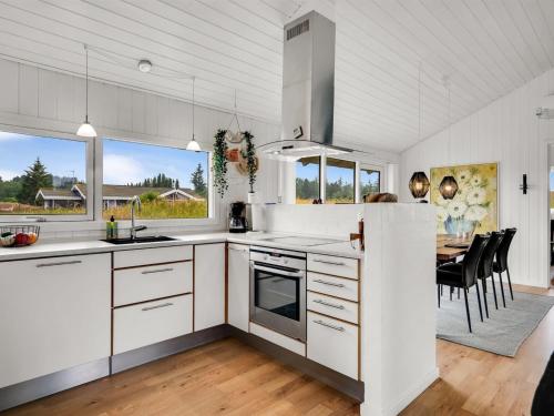 a kitchen with white cabinets and a dining room with a table at Holiday Home Bothilda - 660m from the sea by Interhome in Bindslev
