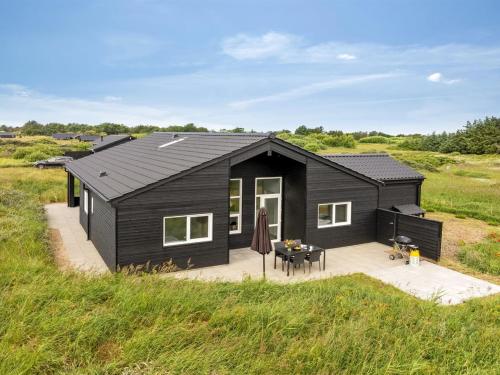 a black house with a patio in a field at Holiday Home Grith - 1km from the sea by Interhome in Hirtshals