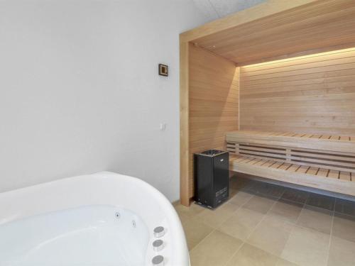 a bath tub in a bathroom with a wooden wall at Holiday Home Grith - 1km from the sea by Interhome in Hirtshals