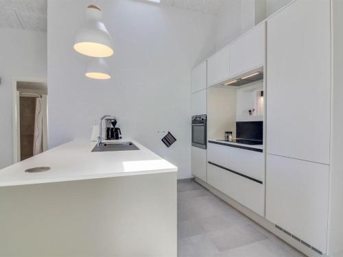 a white kitchen with white cabinets and a sink at Holiday Home Grith - 1km from the sea by Interhome in Hirtshals