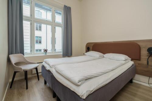 a bedroom with a bed and a chair and a window at MAYA Apartments - Parkveien in Oslo