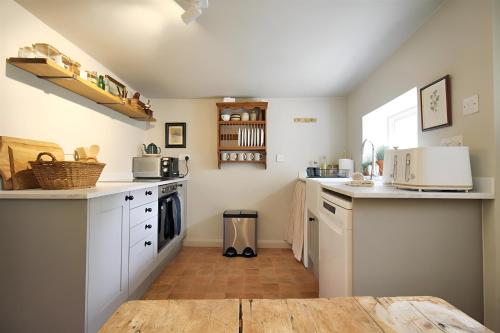 a kitchen with white cabinets and a wooden table at 28 Millgate Cosy Dog Friendly Cottage in Aylsham in Aylsham