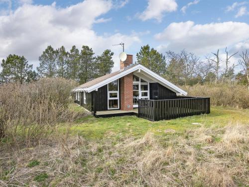 a small black house in a field with grass at Holiday Home Eliana - 350m from the sea by Interhome in Strandby