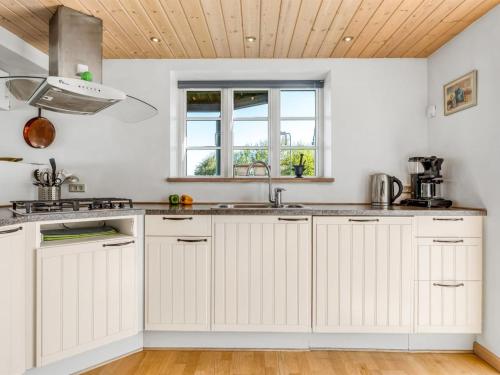a kitchen with white cabinets and a wooden ceiling at Holiday Home Tara - 300m from the sea by Interhome in Læsø