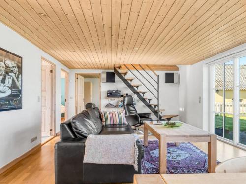 a living room with a black leather couch and a wooden ceiling at Holiday Home Tara - 300m from the sea by Interhome in Læsø
