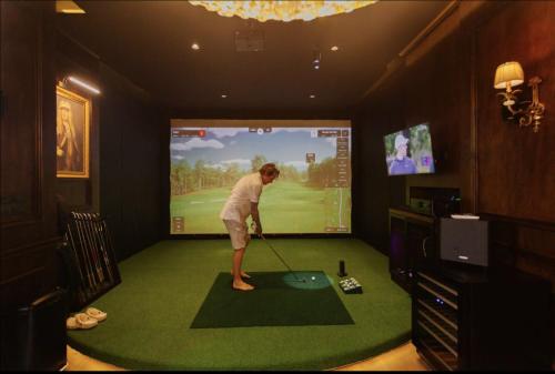 a man playing golf in a room with a tv at Palm Villa - Award Winning Modern Luxury & Exclusive Villa in Chiang Mai