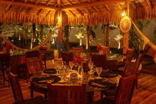 a dining room with tables and chairs and a thatch roof at Hotel de Charme Illuminare Stile in Fortim