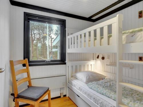 a bedroom with two bunk beds and a chair at Holiday Home Djuna - 200m from the sea by Interhome in Læsø