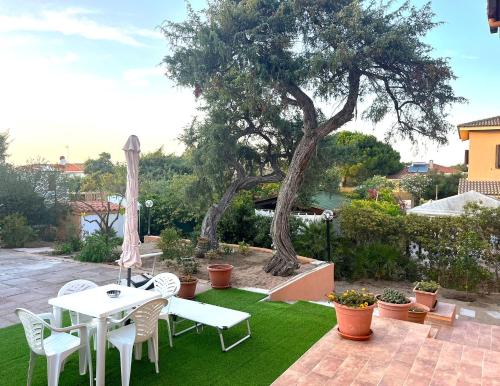 a patio with a table and chairs and a tree at Appartamento in villa privata -villa rialto- in Marina di Sorso