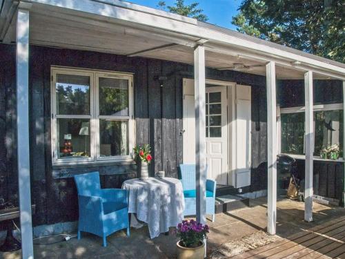 a porch with a table and blue chairs on it at Holiday Home Laurine - 2-7km from the sea by Interhome in Jerup