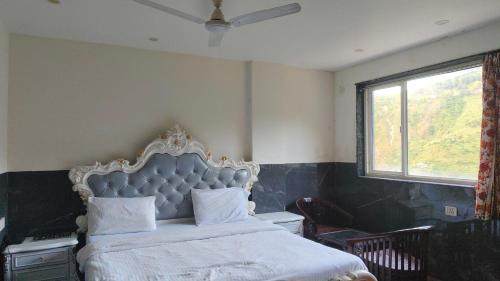 a bedroom with a large bed with a large window at Sach Naina Residency, Mussoorie in Jāmb