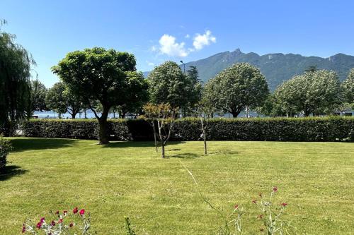 a field of grass with trees and a hedge at Studio bord du lac terrasse in Aix-les-Bains