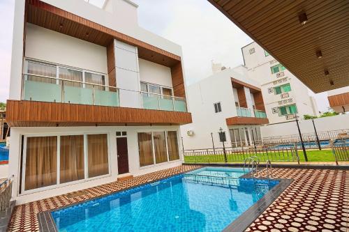a swimming pool in front of a building at ASJ Holiday Villa in Puducherry