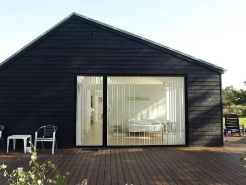 a black house with a large sliding glass door at Holiday Home Jonce - 400m from the sea by Interhome in Jerup