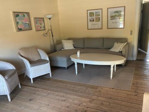 Una sala de estar con un sofá, una mesa y sillas. en Apartment Faustine - 500m from the sea by Interhome, en Skagen