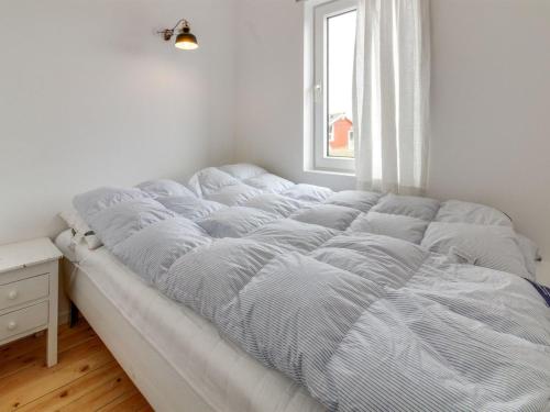 a bed in a white room with a window at Holiday Home Sohvi - 450m from the sea by Interhome in Lakolk